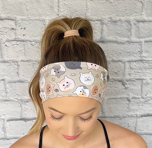 Woman wearing a headband with cat pattern against a white brick wall.