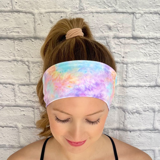 Woman with hair in curled ponytail wearing stretchy, flat, pastel color tie dye headband.