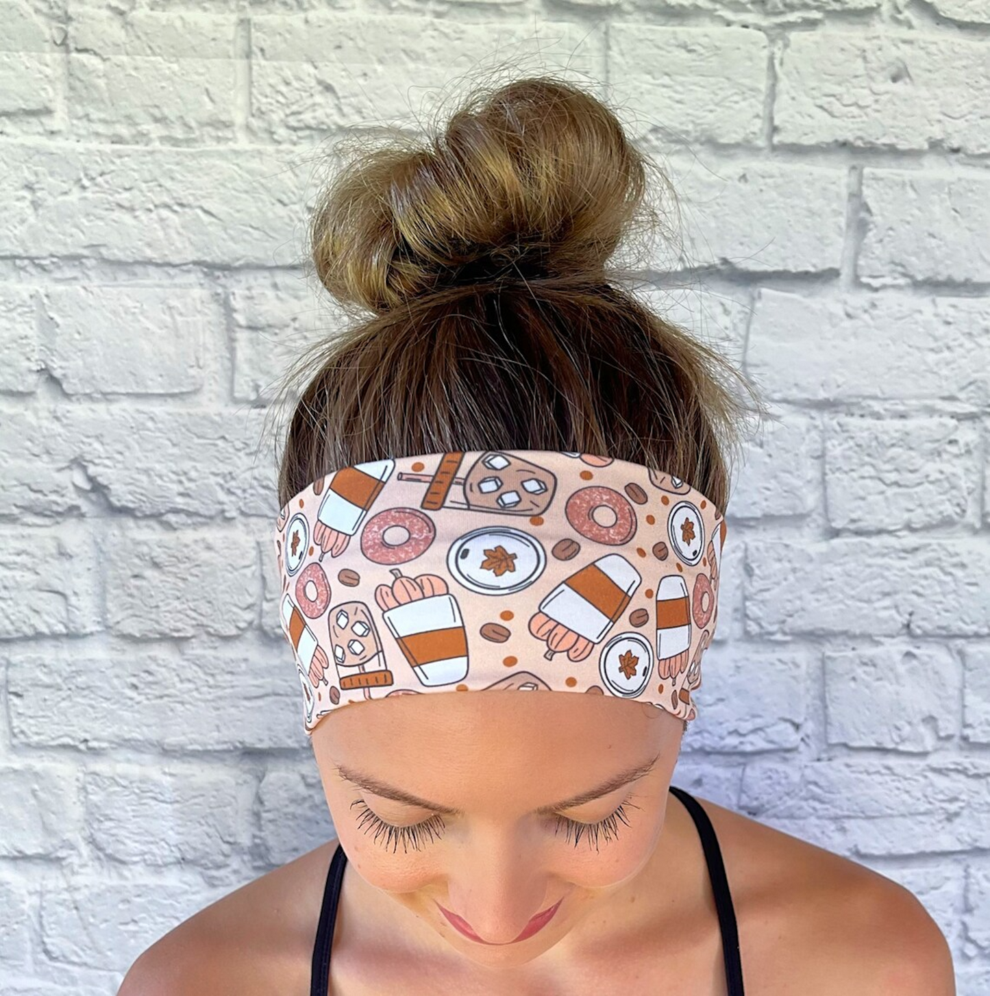 Woman with hair in bun wearing flat, stretchy headband with pumpkin spice fall theme print.