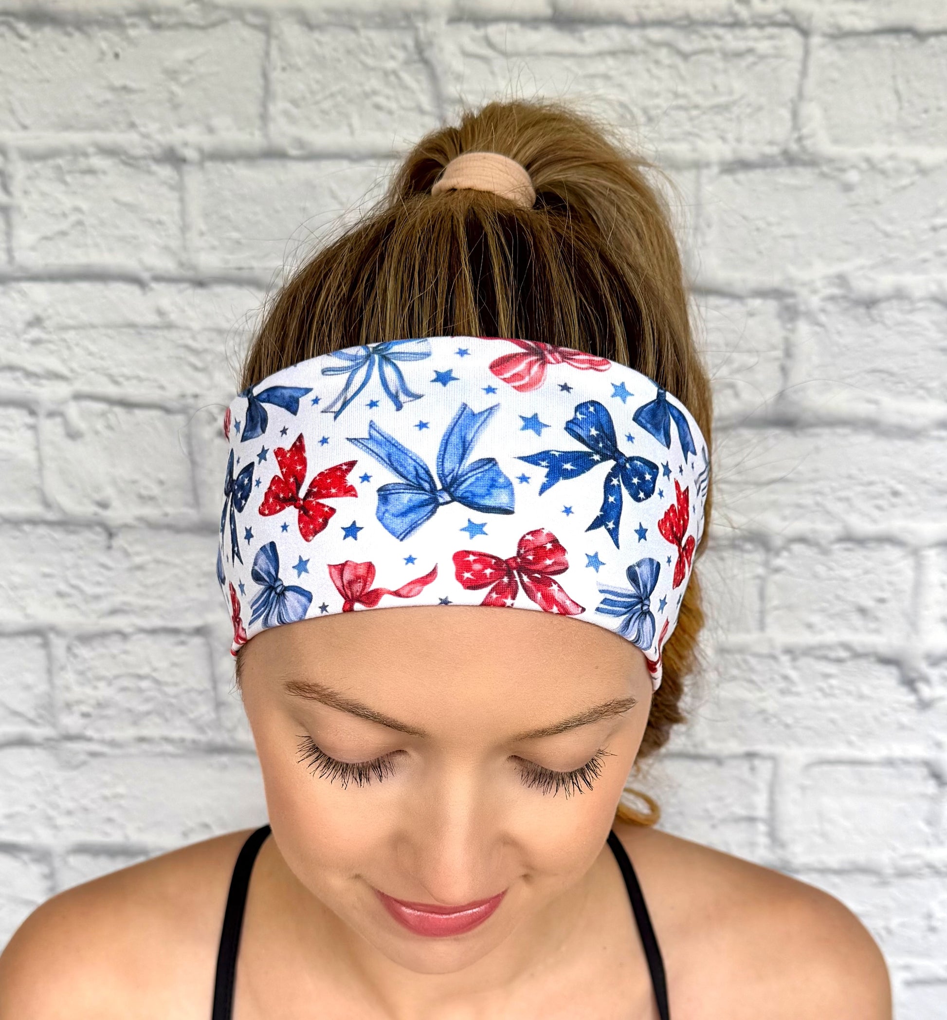 Flat, stretchy, white headband with red and blue bow print and blue stars.