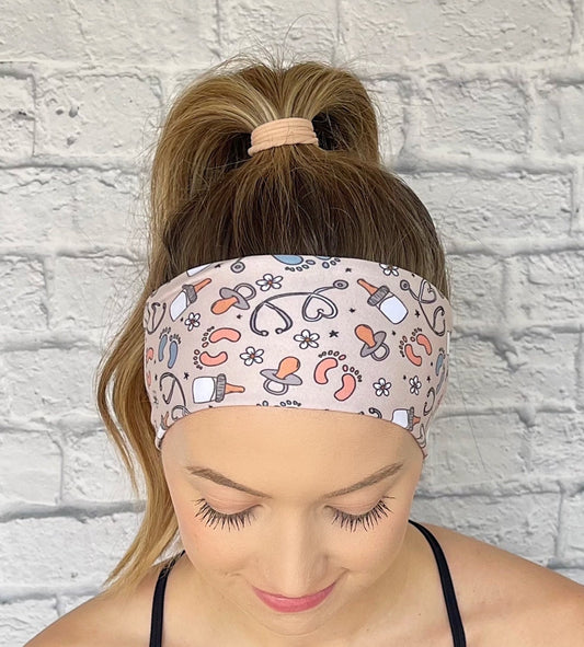 Woman with hair in ponytail wearing flat, stretchy headband in tan color with baby theme print.
