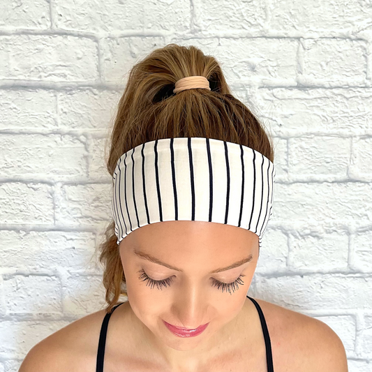 Woman with hair in ponytail wearing headband in white with navy pinstripe print.