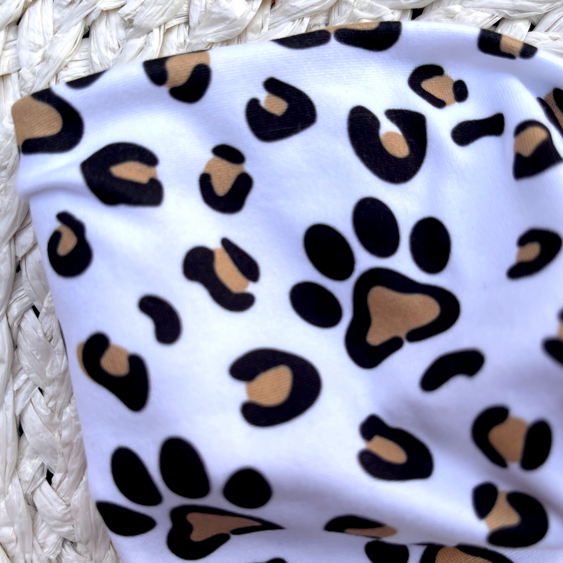 Wide, white, twisted headband with brown and black dog paws and cheetah print.