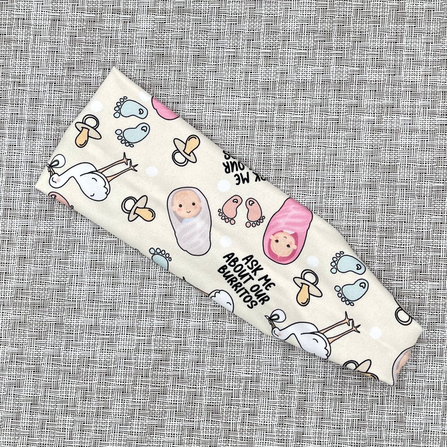 Cream color, stretchy headband, with baby theme print and "ask me about our burritos".