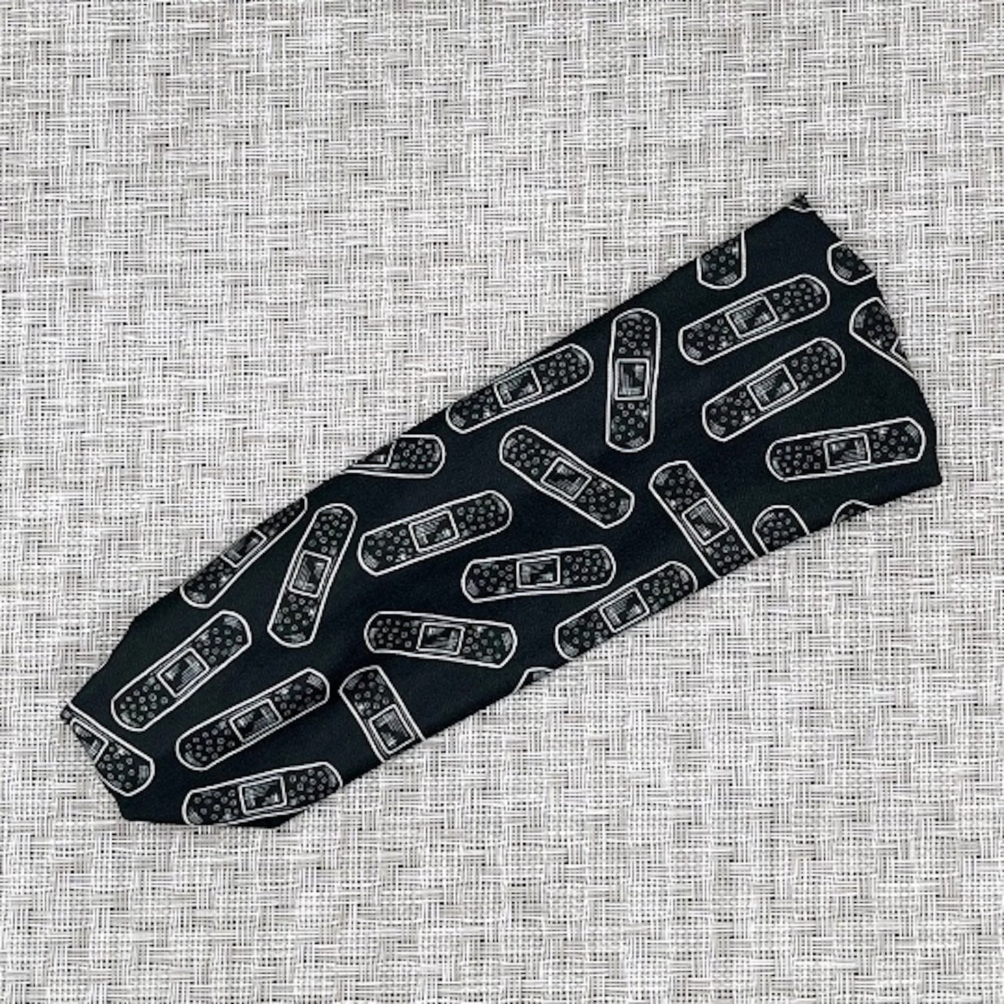 Flat, stretchy headband in black with white bandage print.