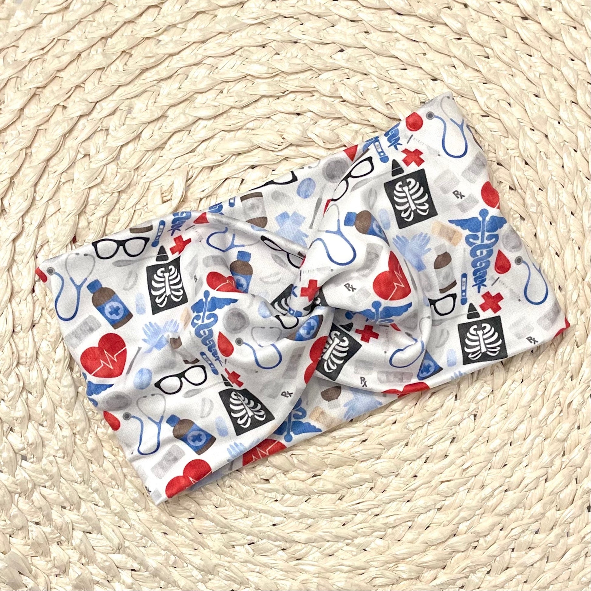 Wide, twisted headband in light blue, red, and black medical theme print.