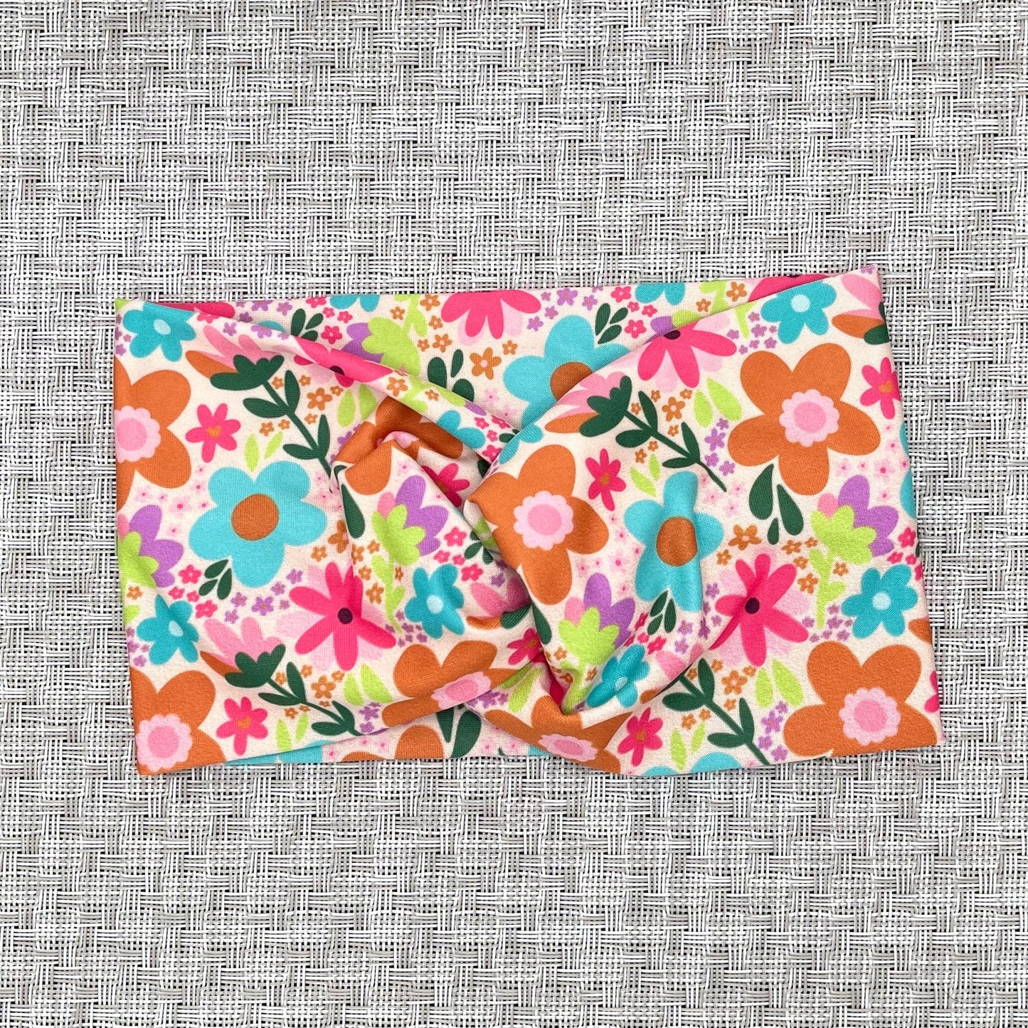 Floral-patterned fabric headband on a textured gray background