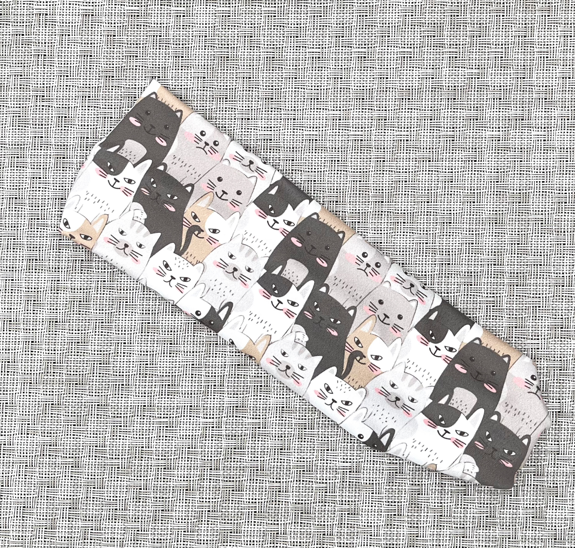 Flat, stretchy headband with gray and tan cat print.