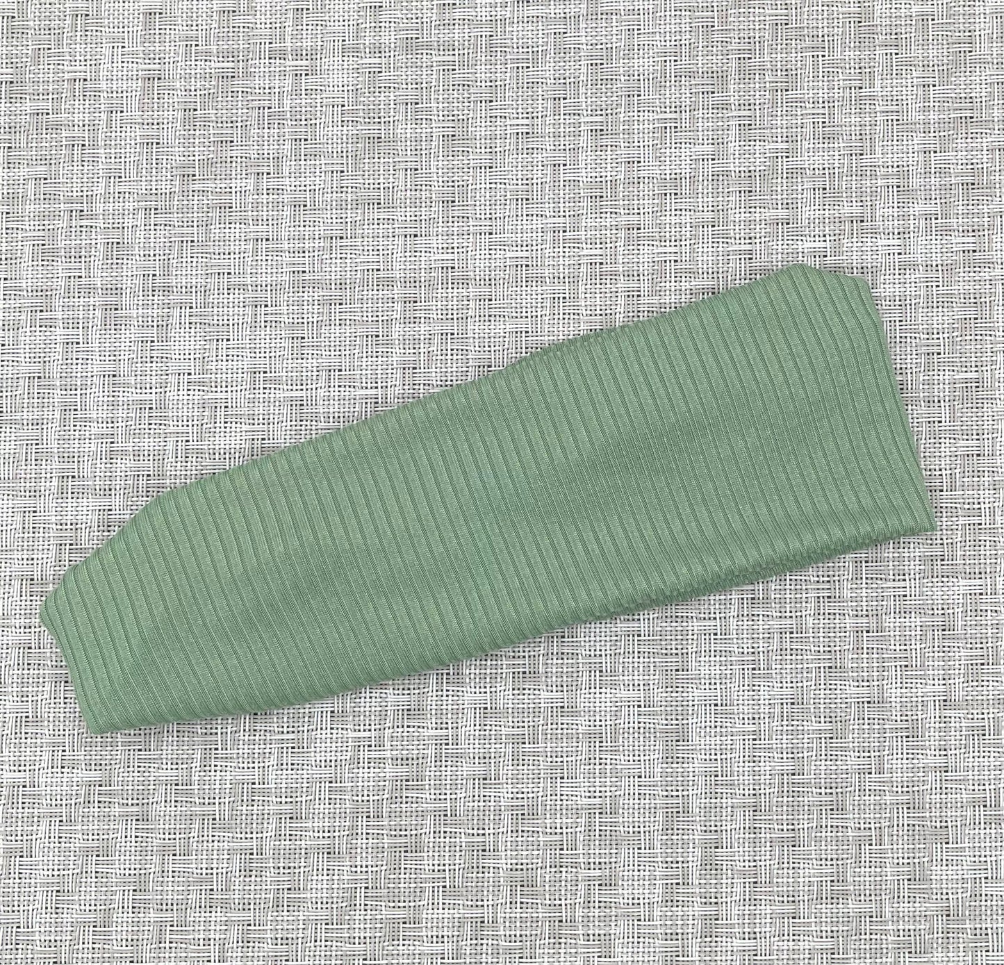 Flat, stretchy headband in green ribbed fabric.