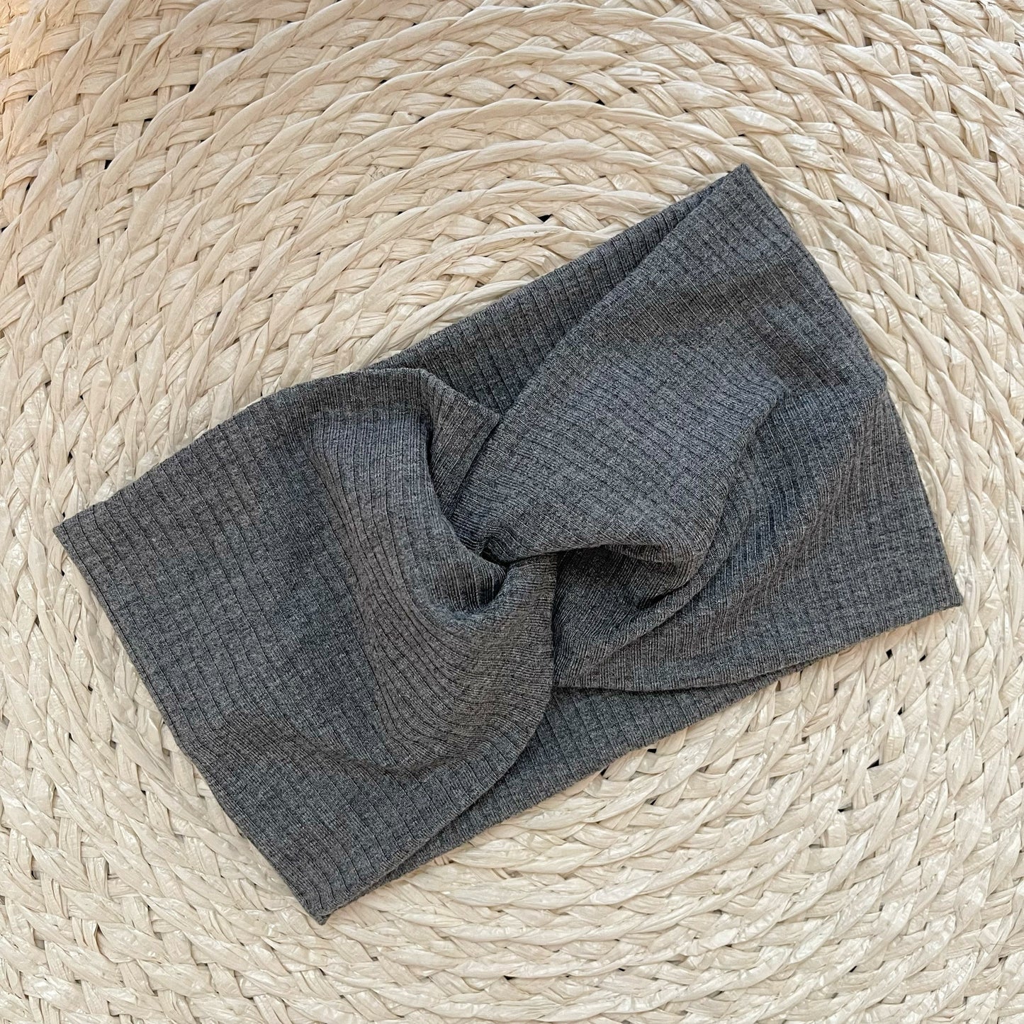 Wide, twisted headband in gray ribbed fabric.