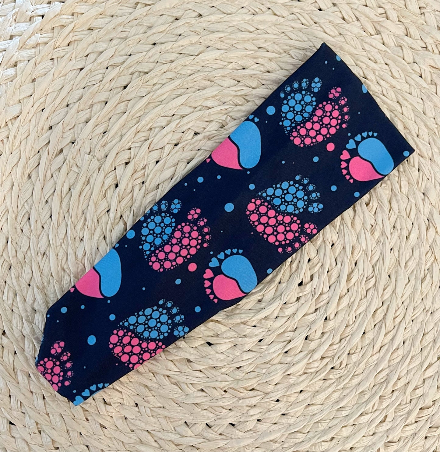 Stretchy, navy color headband with pink and blue baby feet print.