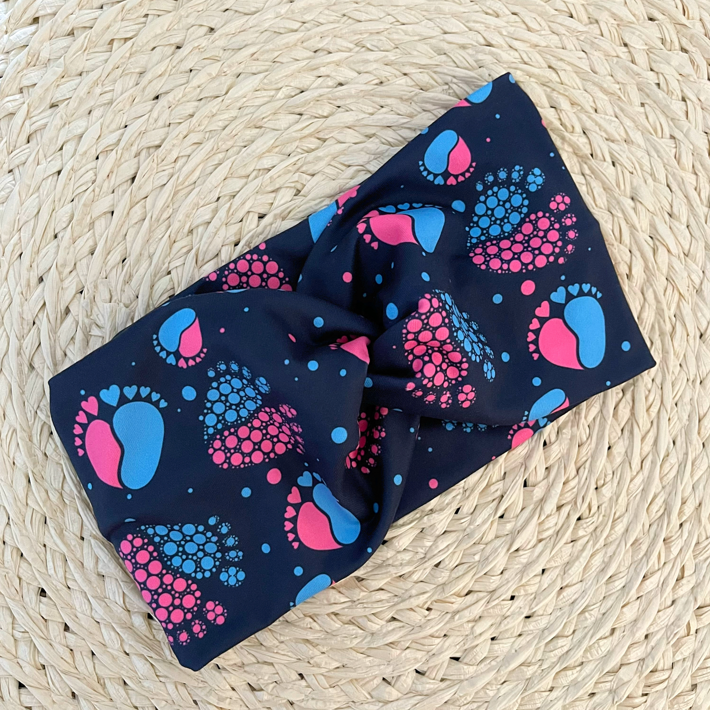 Navy blue, wide twist headband with pink and blue baby feet.
