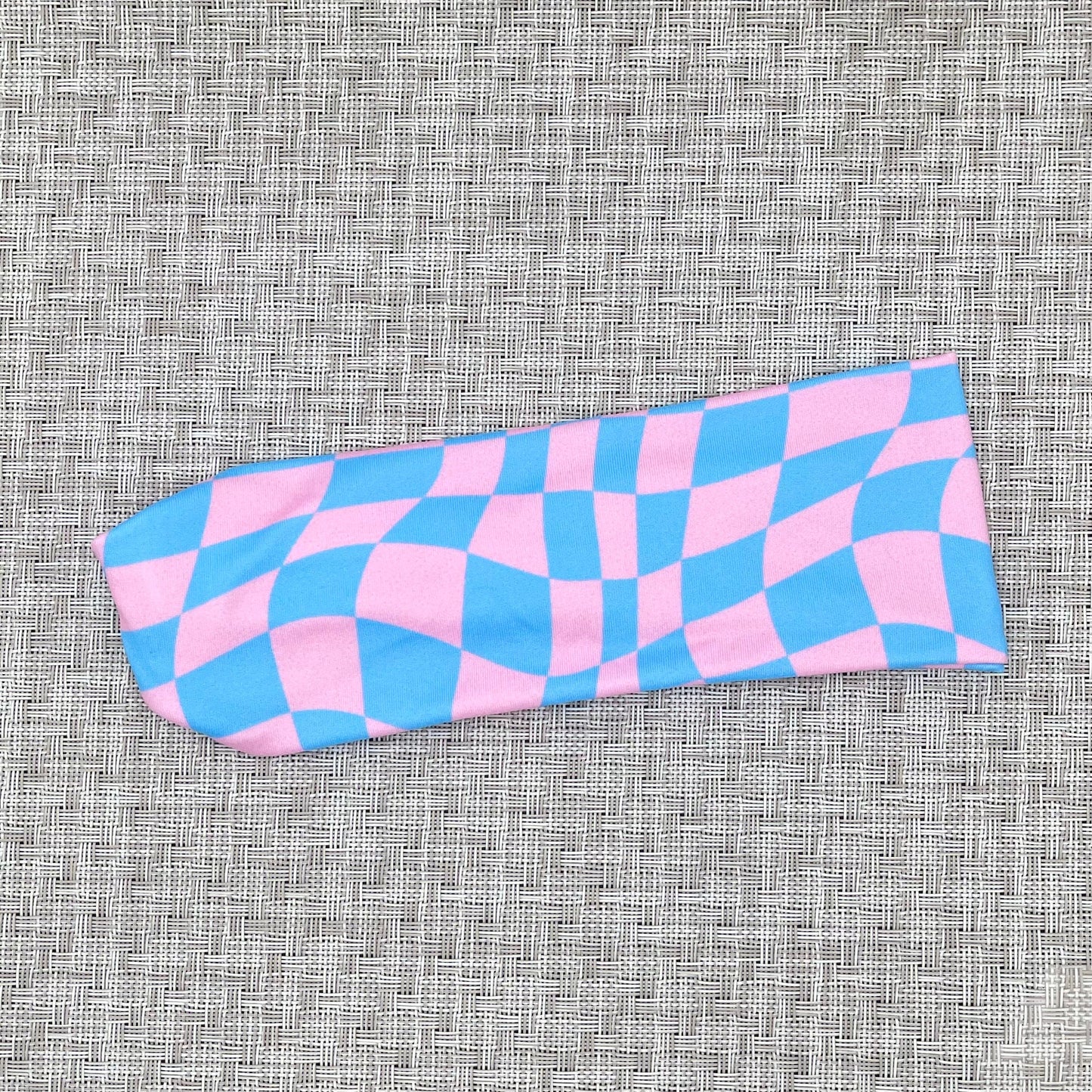 Pink and blue checkered headband on a textured gray background