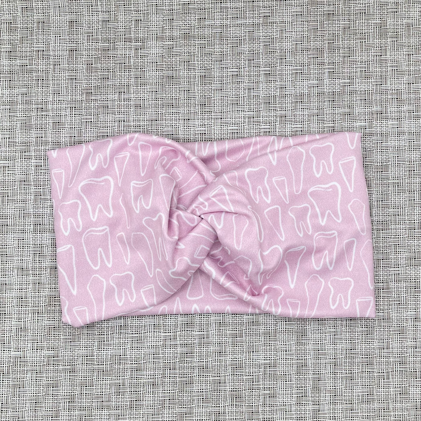 Wide, twisted headband in light pink with white teeth print.