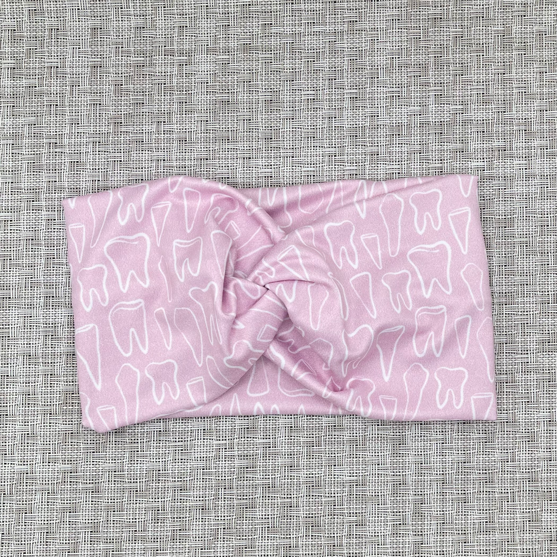 Wide, twisted headband in light pink with white teeth print.