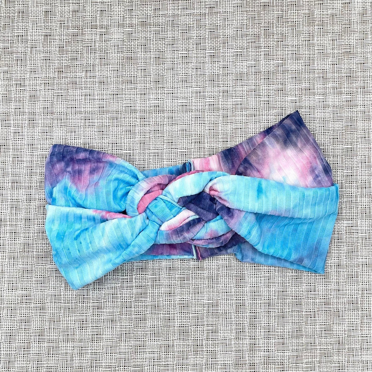 Sailor knot style headband in ribbed fabric with purple and blue tie dye print.