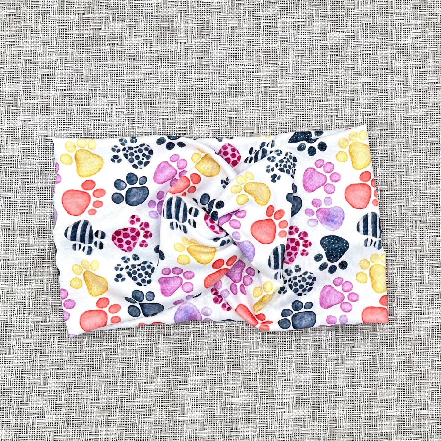 Wide, twisted headband in white with multi-color dog paw print.