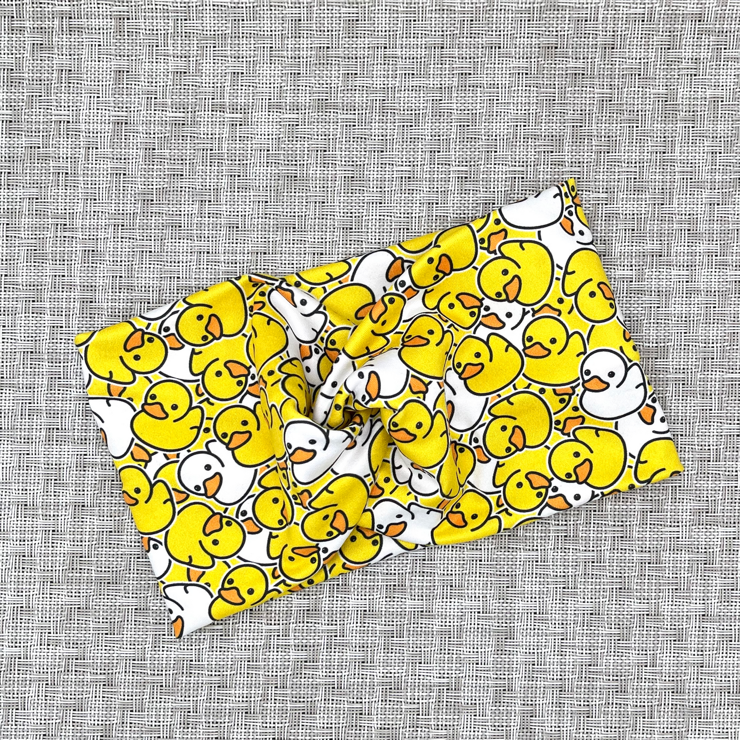 Wide, twisted headband in yellow and white rubber duck print.