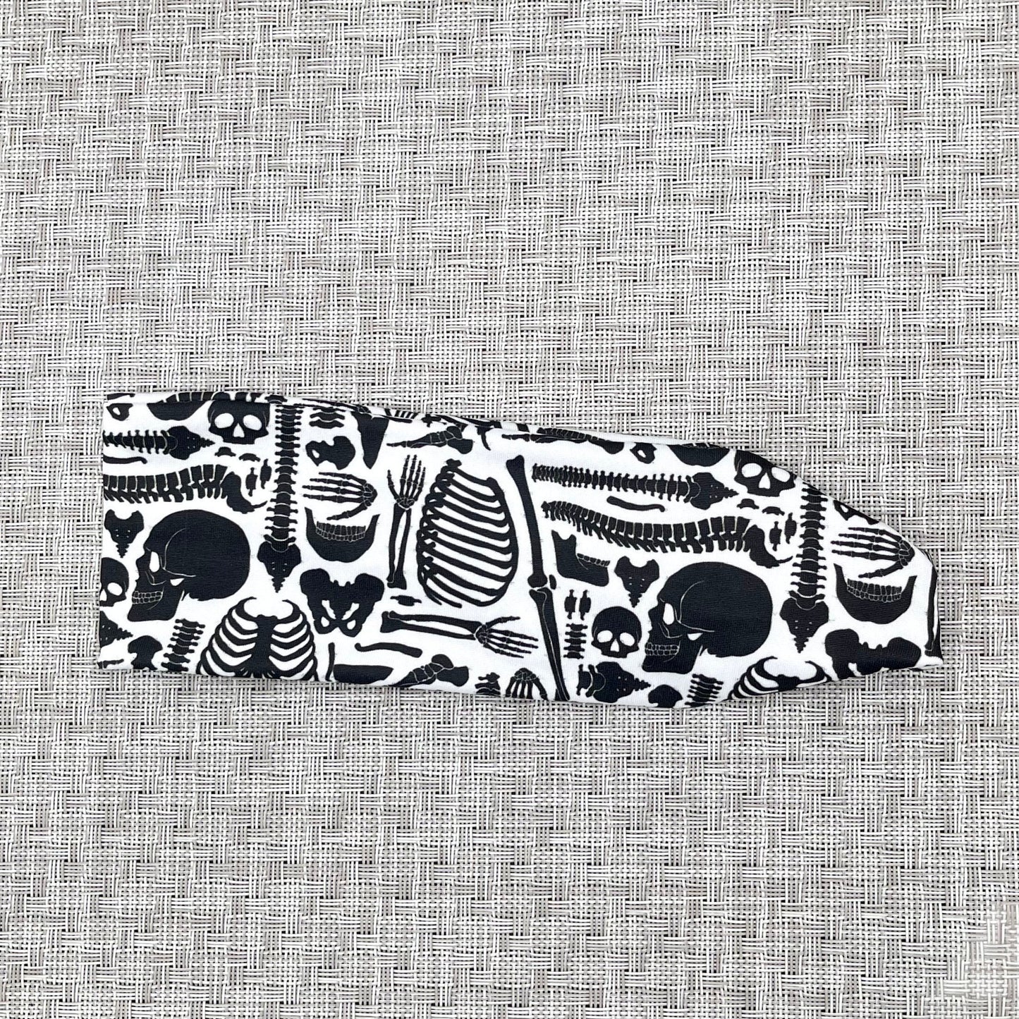 Flat, stretchy headband in white with black skeleton print.