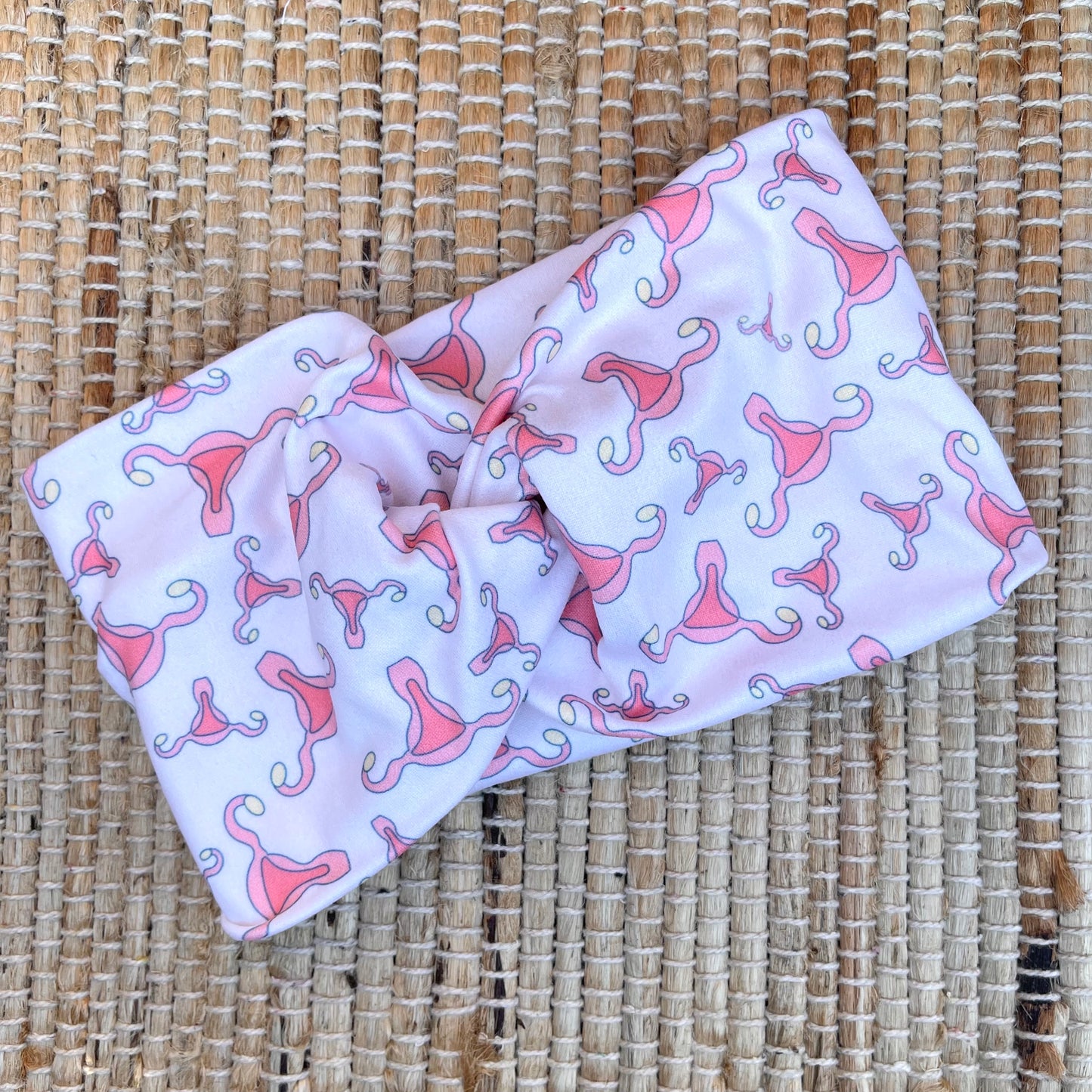 Cream color, wide twist headband with uterus print.