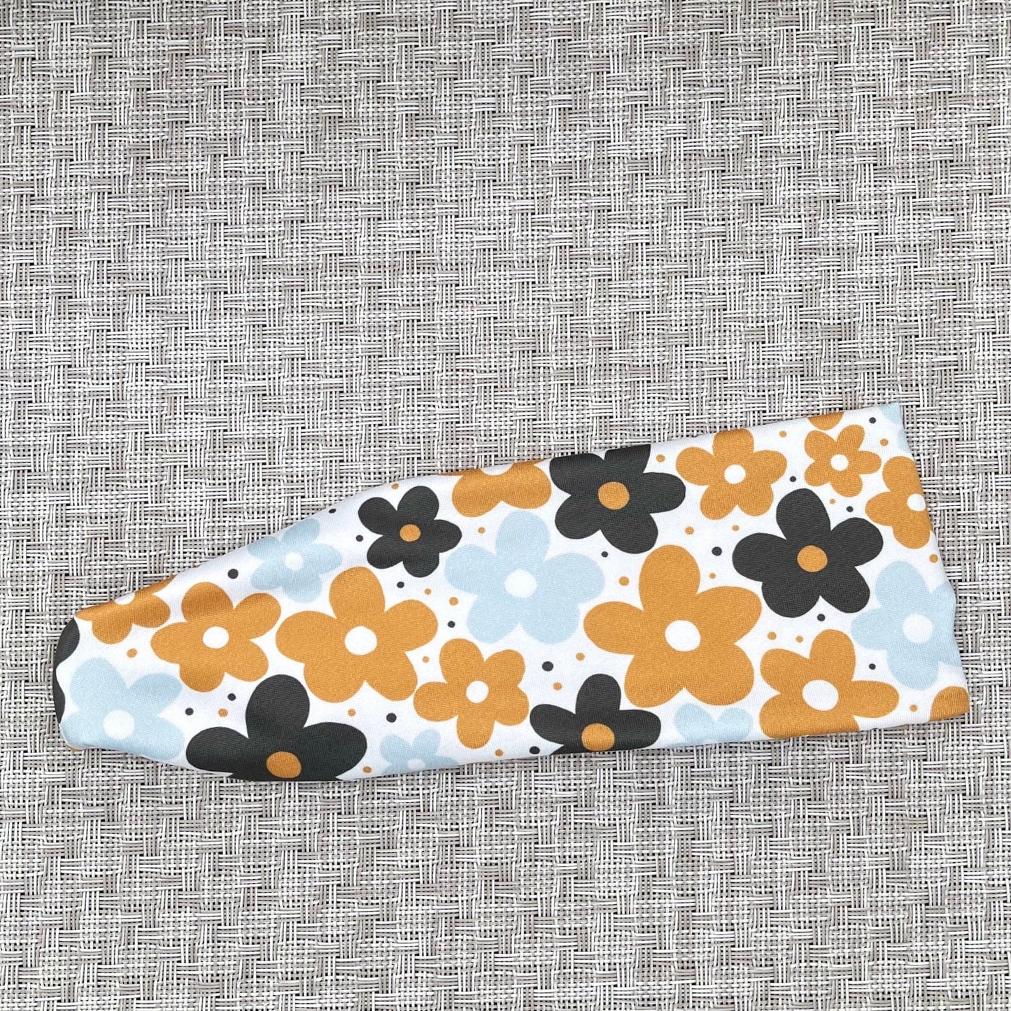 Flat, stretchy headband in yellow, navy, and light blue floral print.