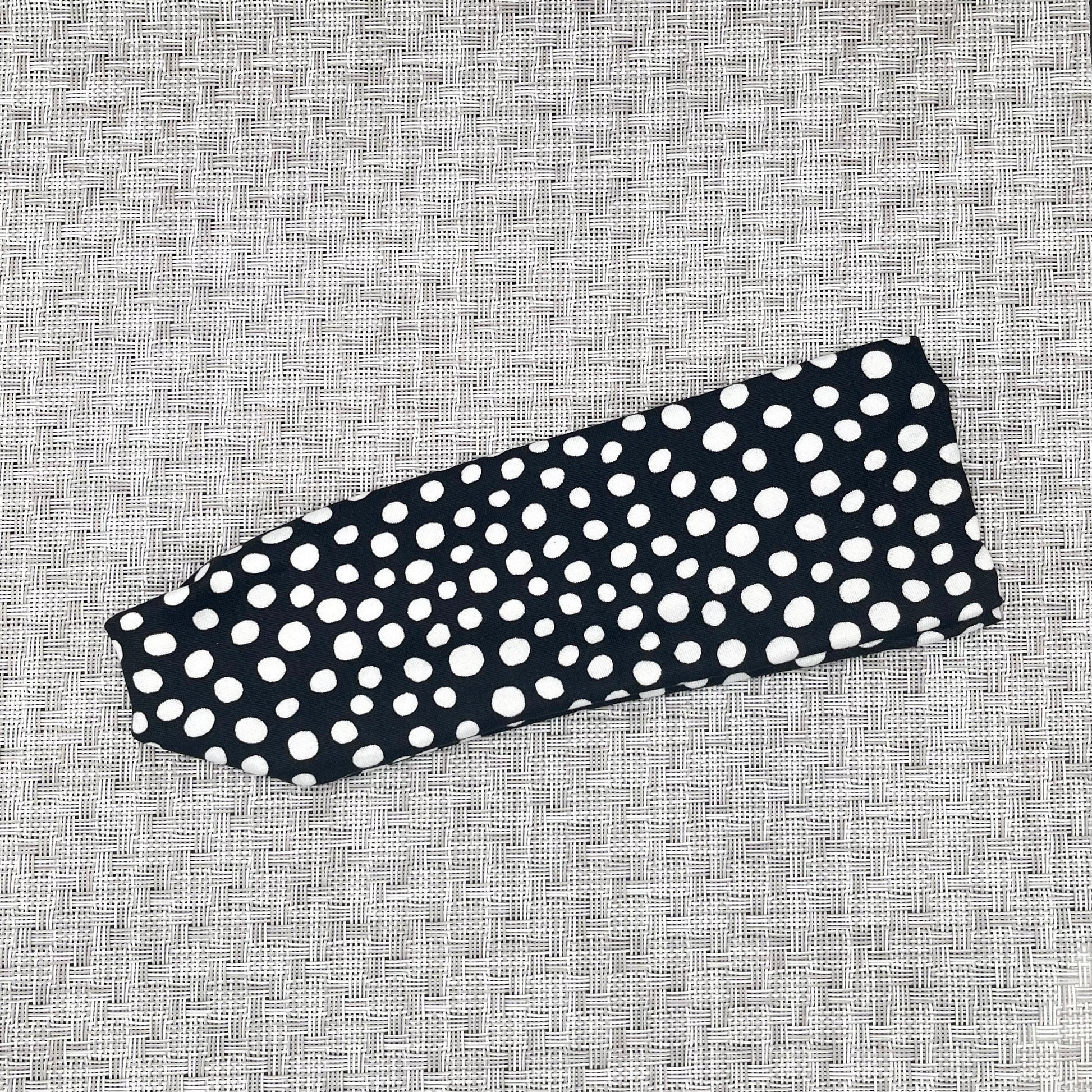 Flat, stretchy headband in black with white polka dot print.