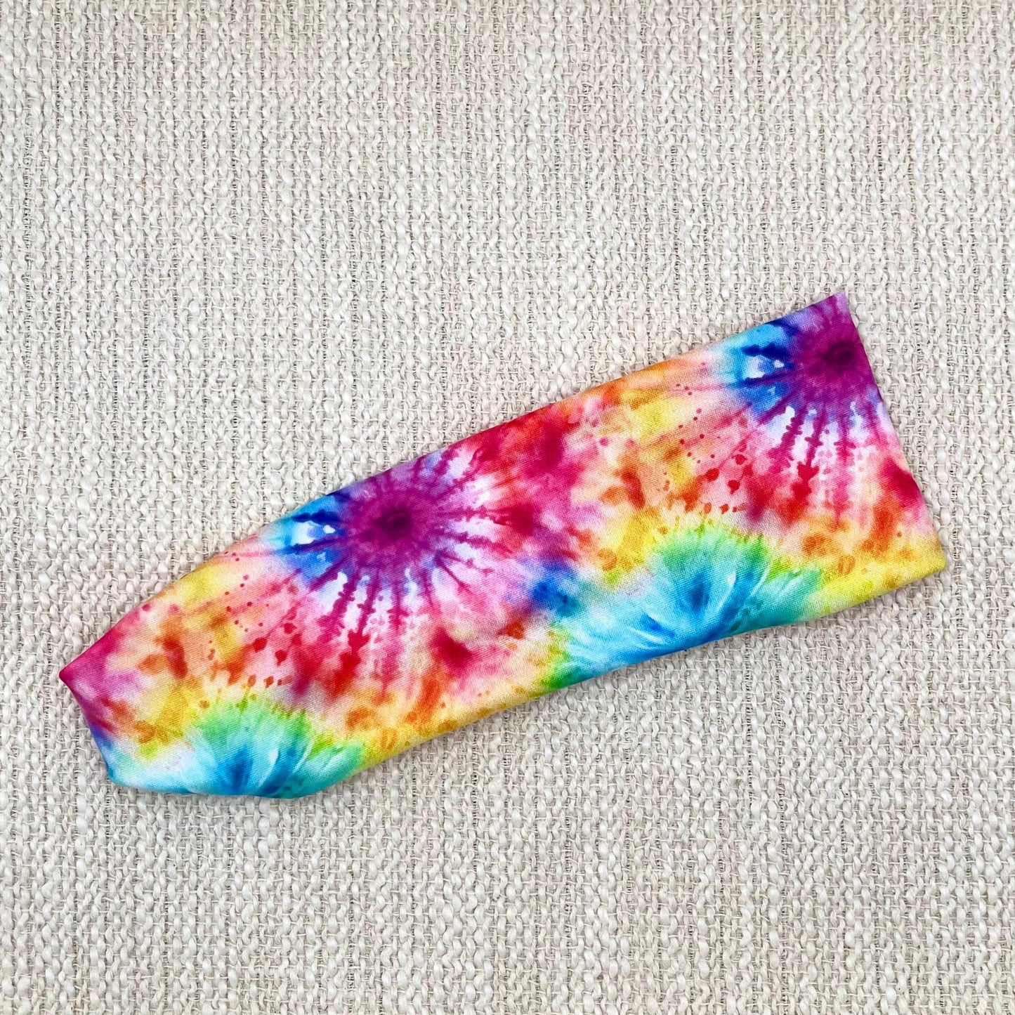 Flat, stretchy headband in rainbow color tie dye pattern.