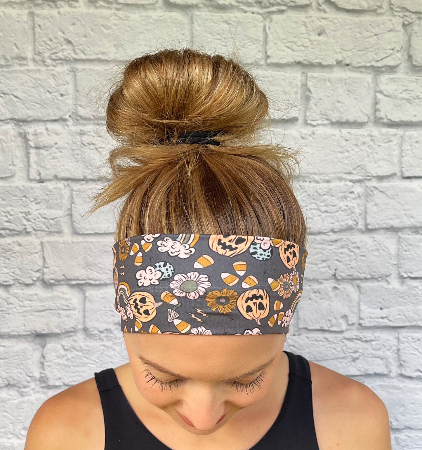Woman with hair in bun wearing flat, stretchy, gray headband with halloween theme print
