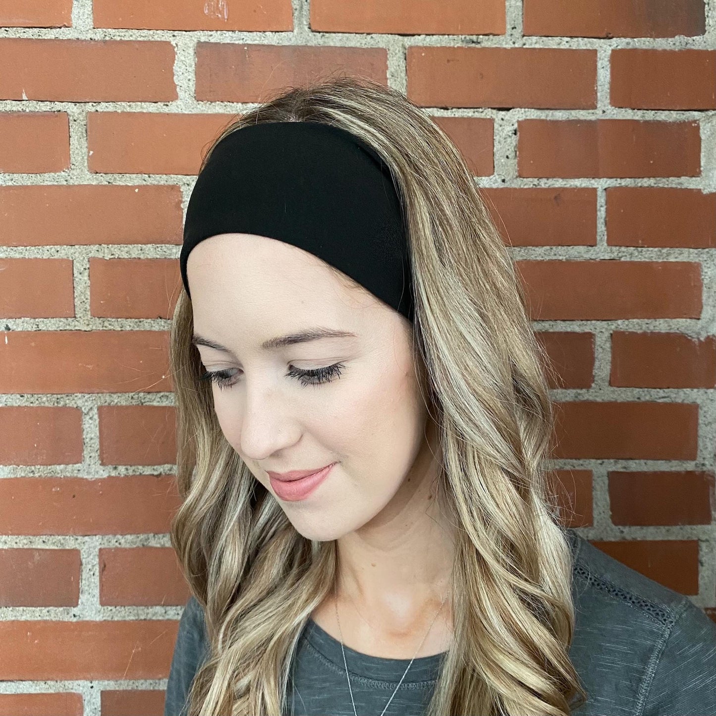 Woman with curled hair wearing black headband.
