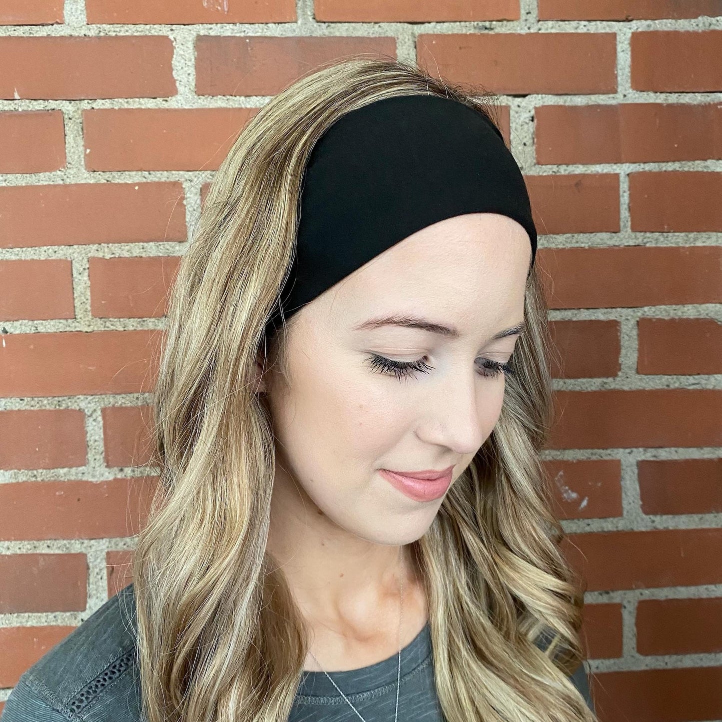 Woman with curled hair wearing black headband.