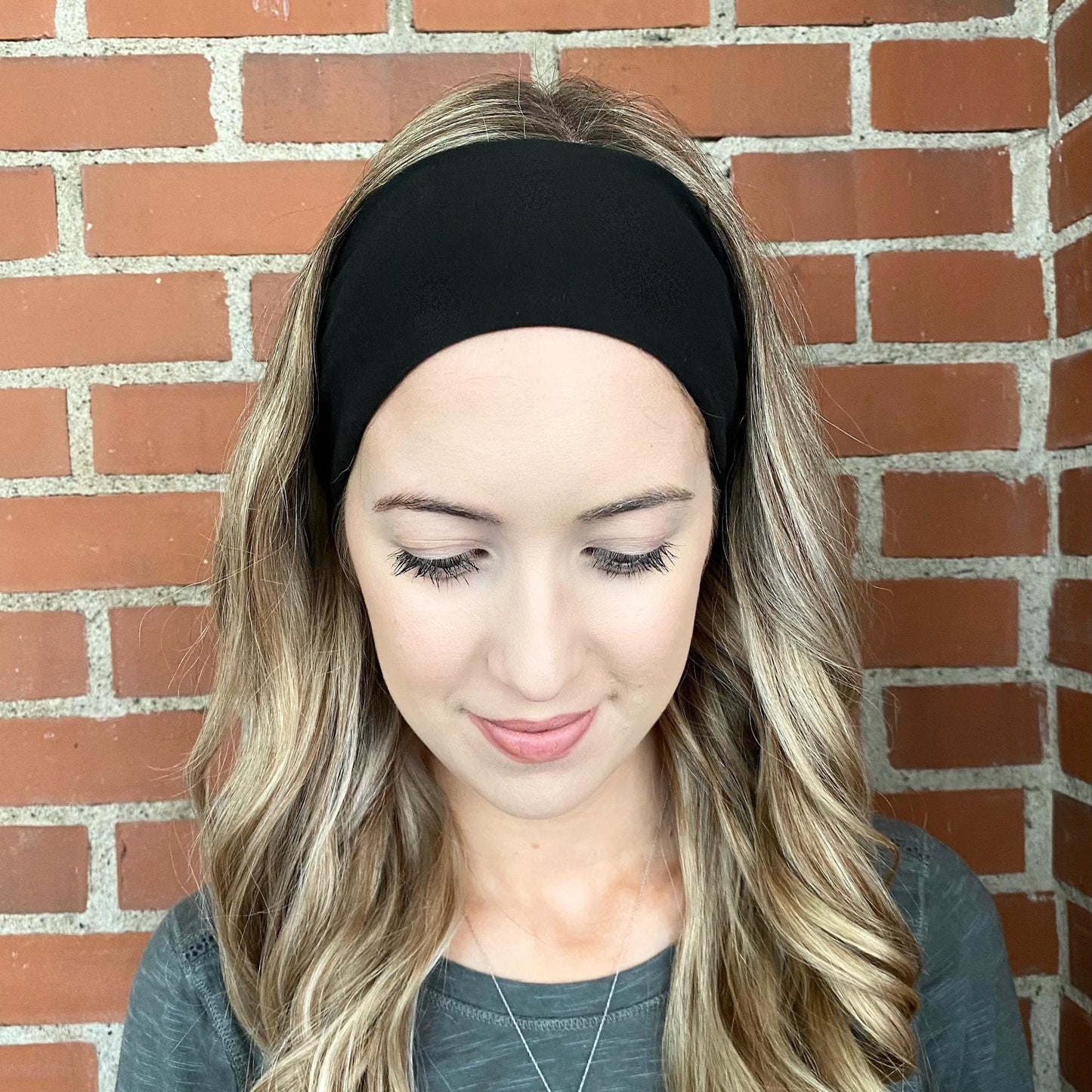 Woman with curled hair wearing black headband.