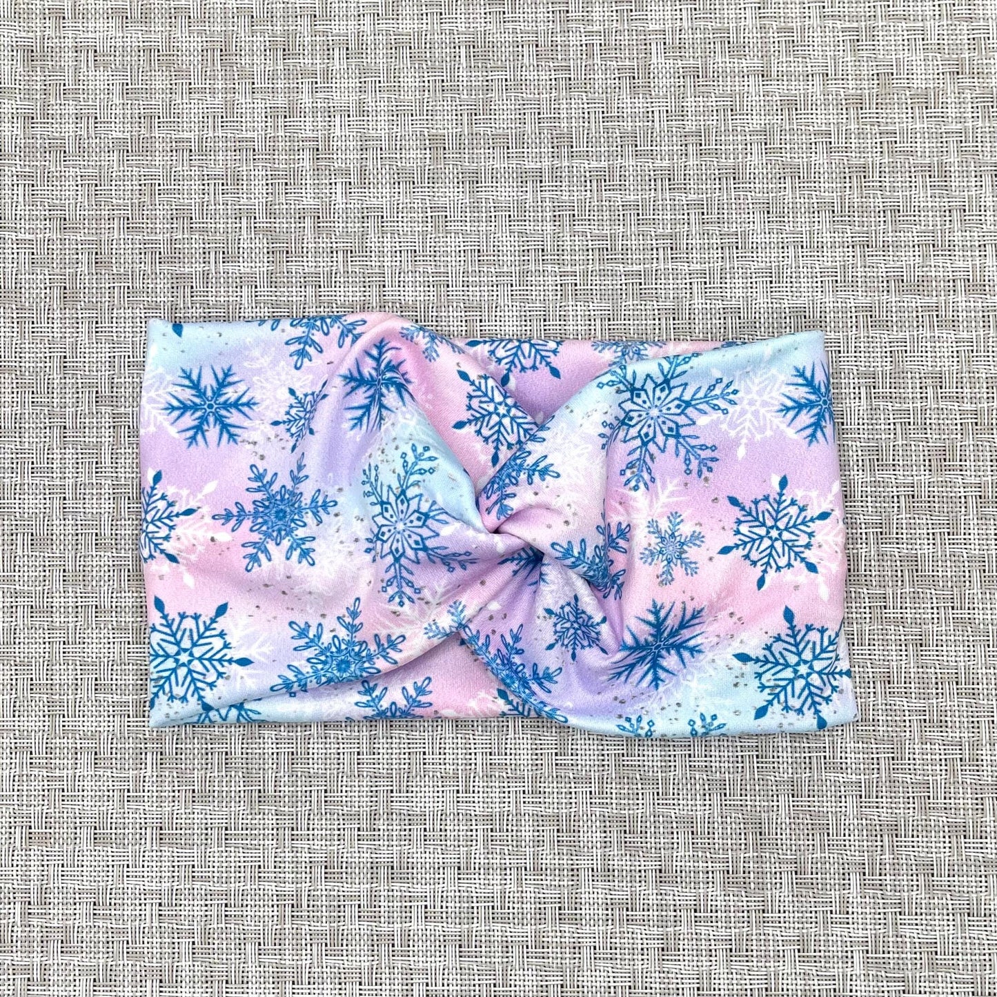 Wide, twisted headband with blue, purple, and pink color with blue and white snowflake print.
