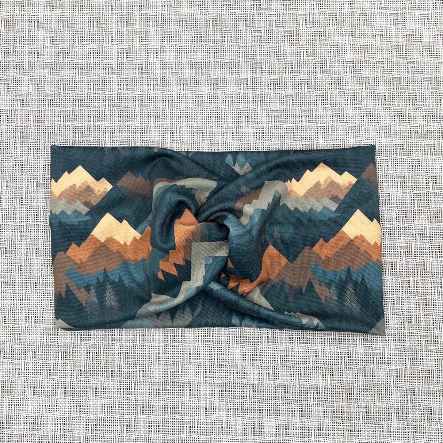 Wide, twisted headband with mountain print in varying shades of blue, brown, and gray.