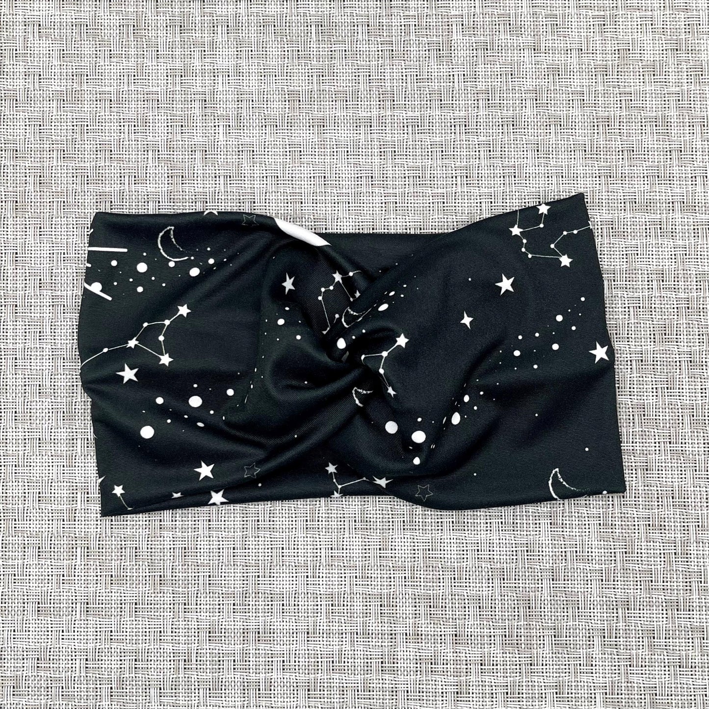 Wide, twisted headband in black with white galaxy theme print.