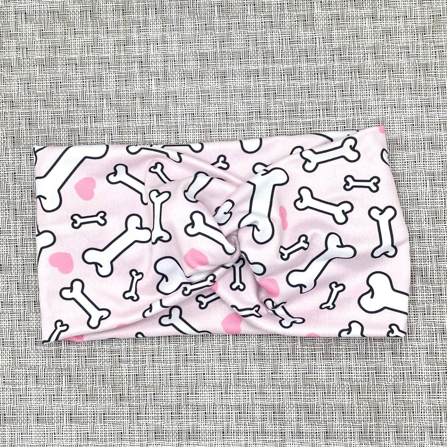 Wide, twisted headband in light pink with dog bone and heart print.