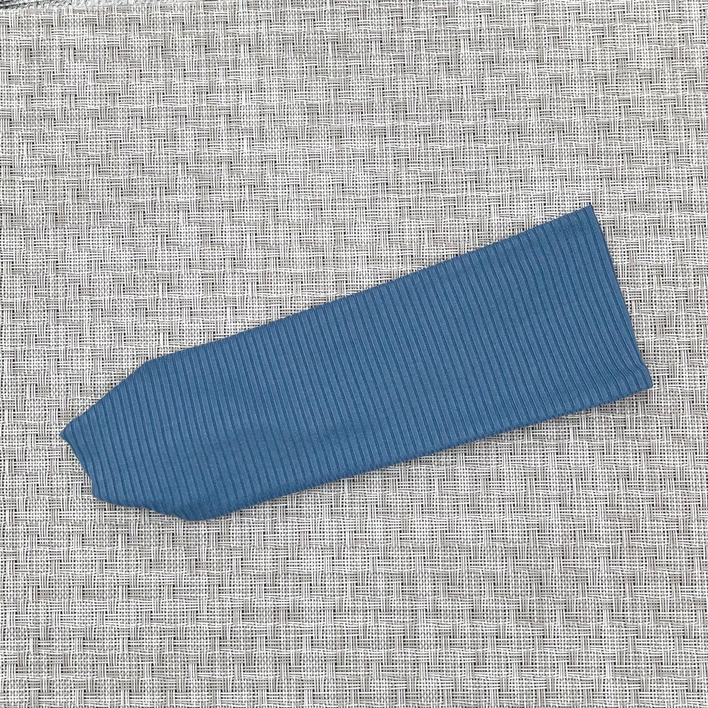 Flat, stretchy headband in blue ribbed fabric.