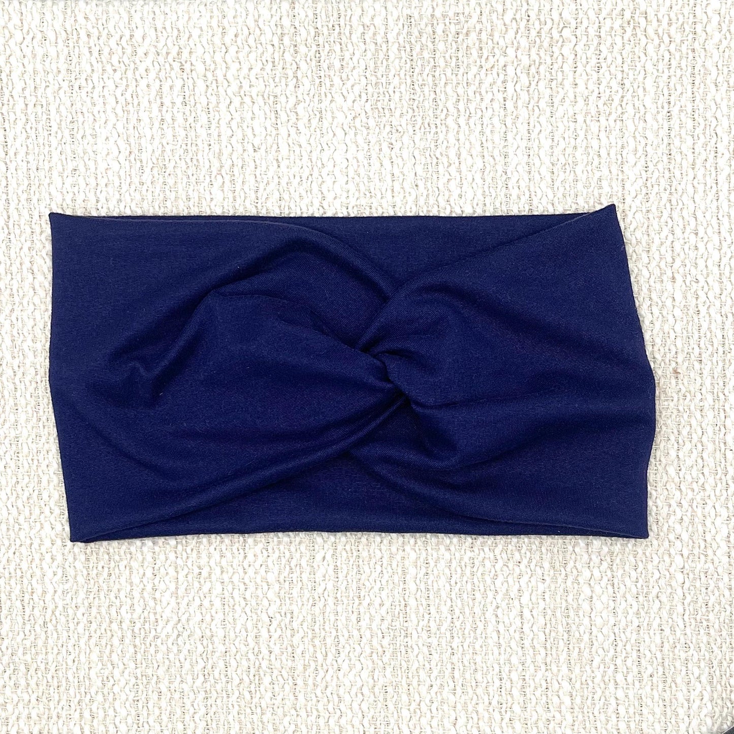 Wide, twisted headband in dark blue/navy color.
