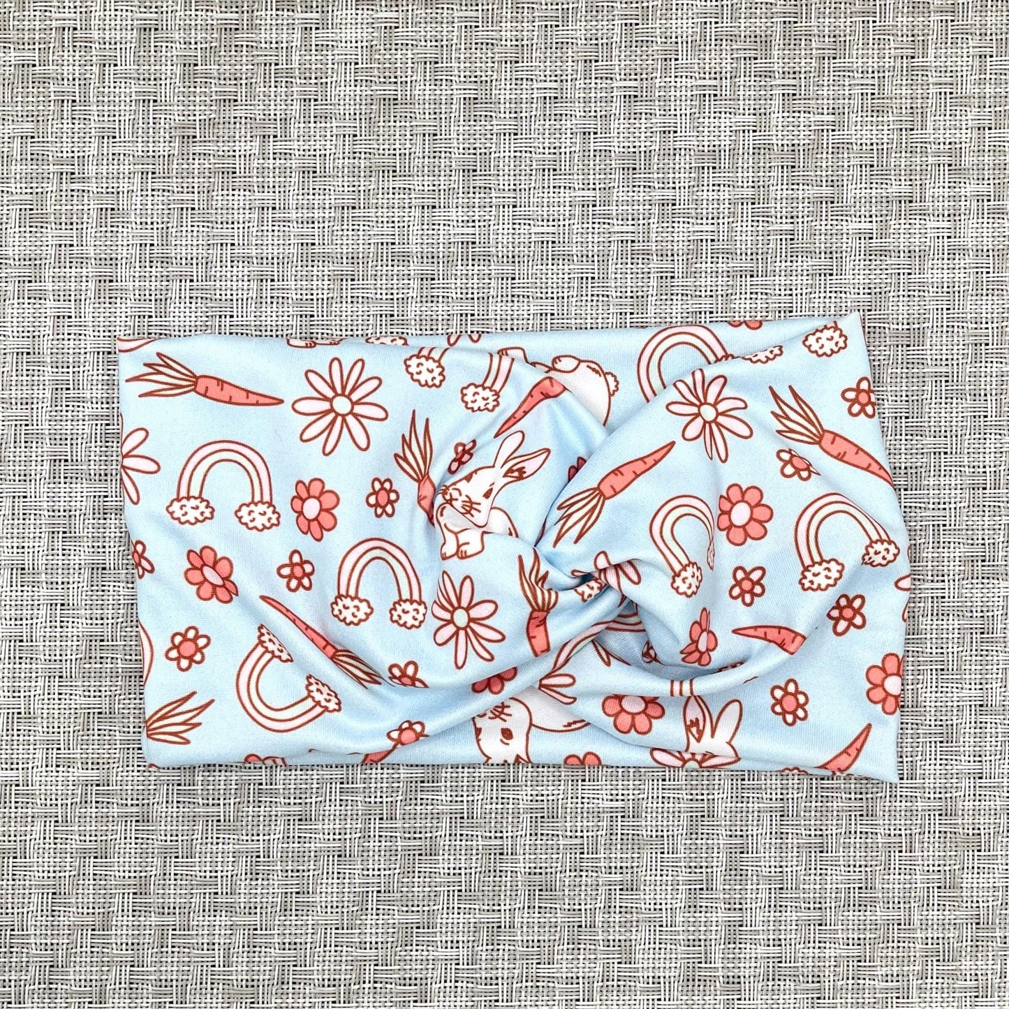 Wide, twisted, light blue headband with Easter theme print.
