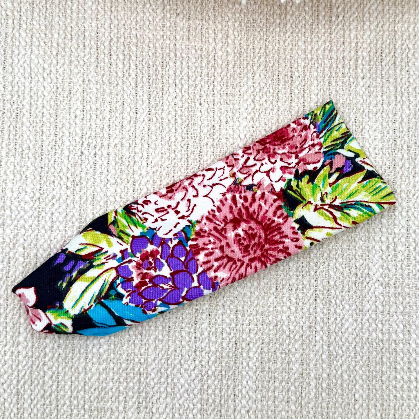 Flat, stretchy headband in black with lime green, pink, and white floral print.