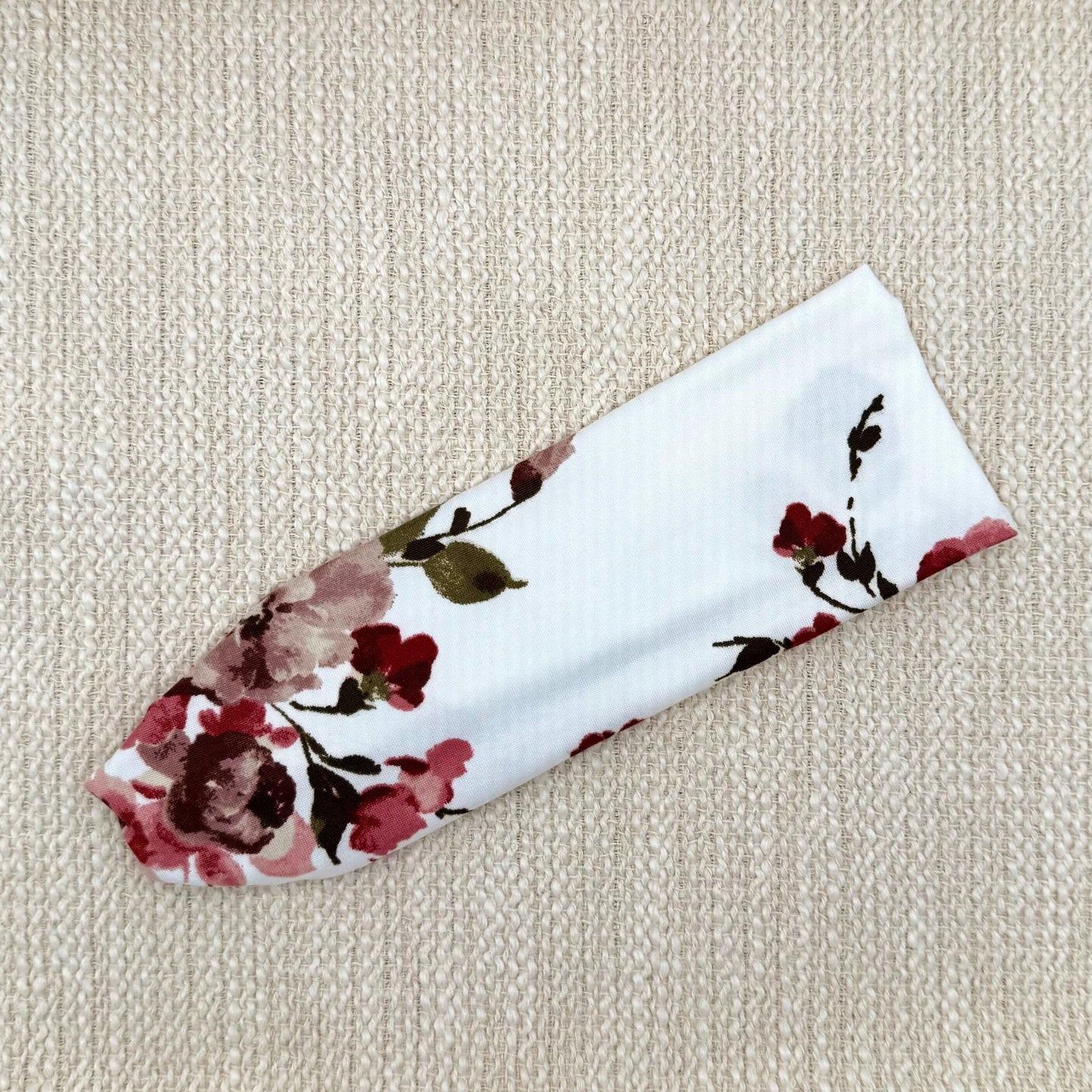 Flat, stretchy headband in white with maroon rose print.
