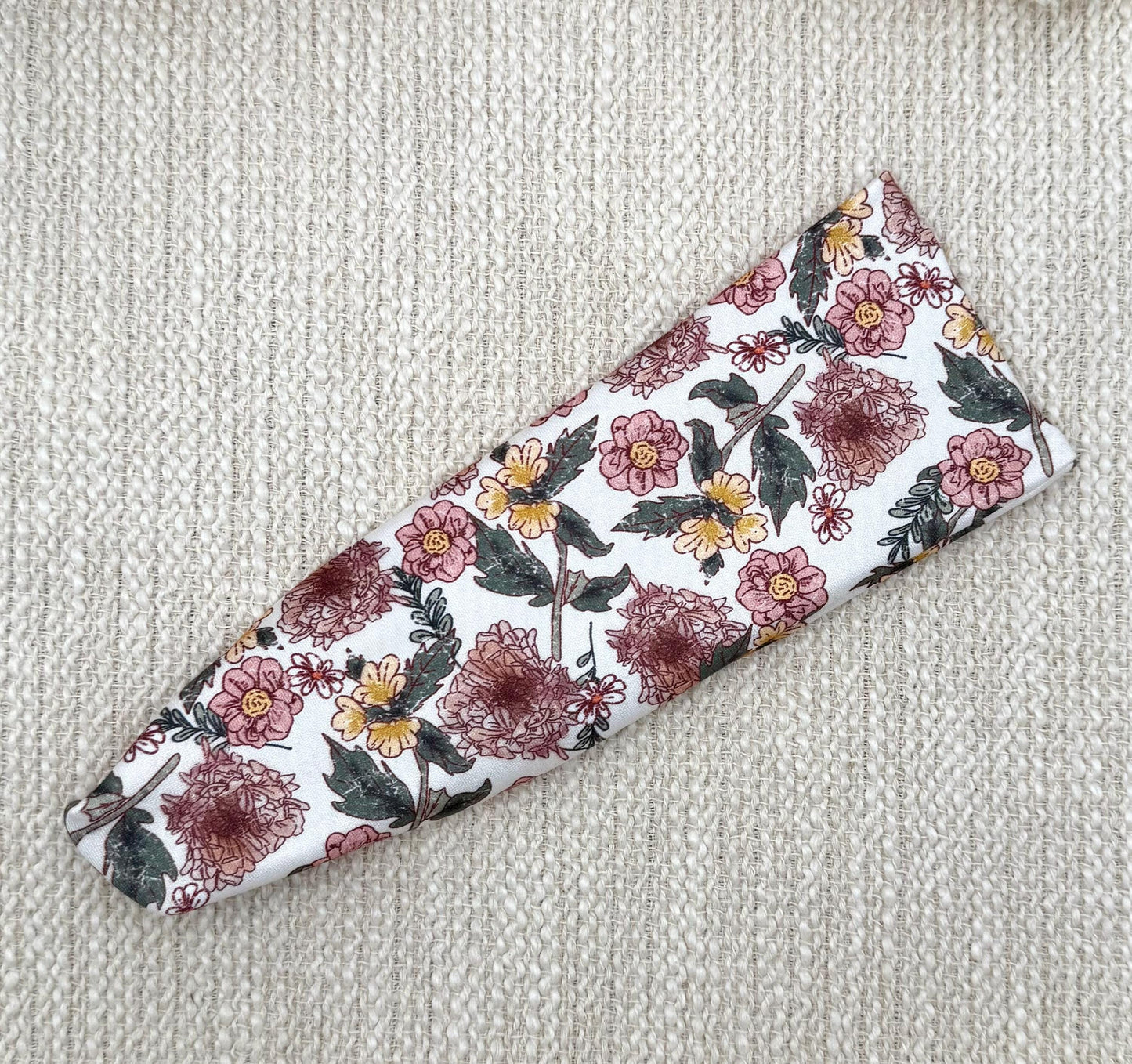 Flat, stretchy headband in white with pink and yellow flower print.