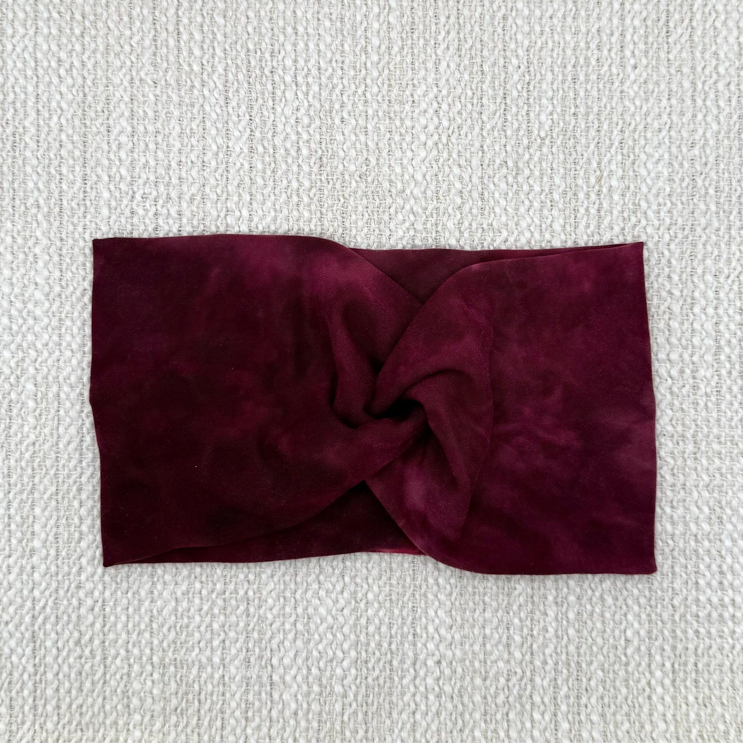 Wide, twisted headband in maroon tie dye print.