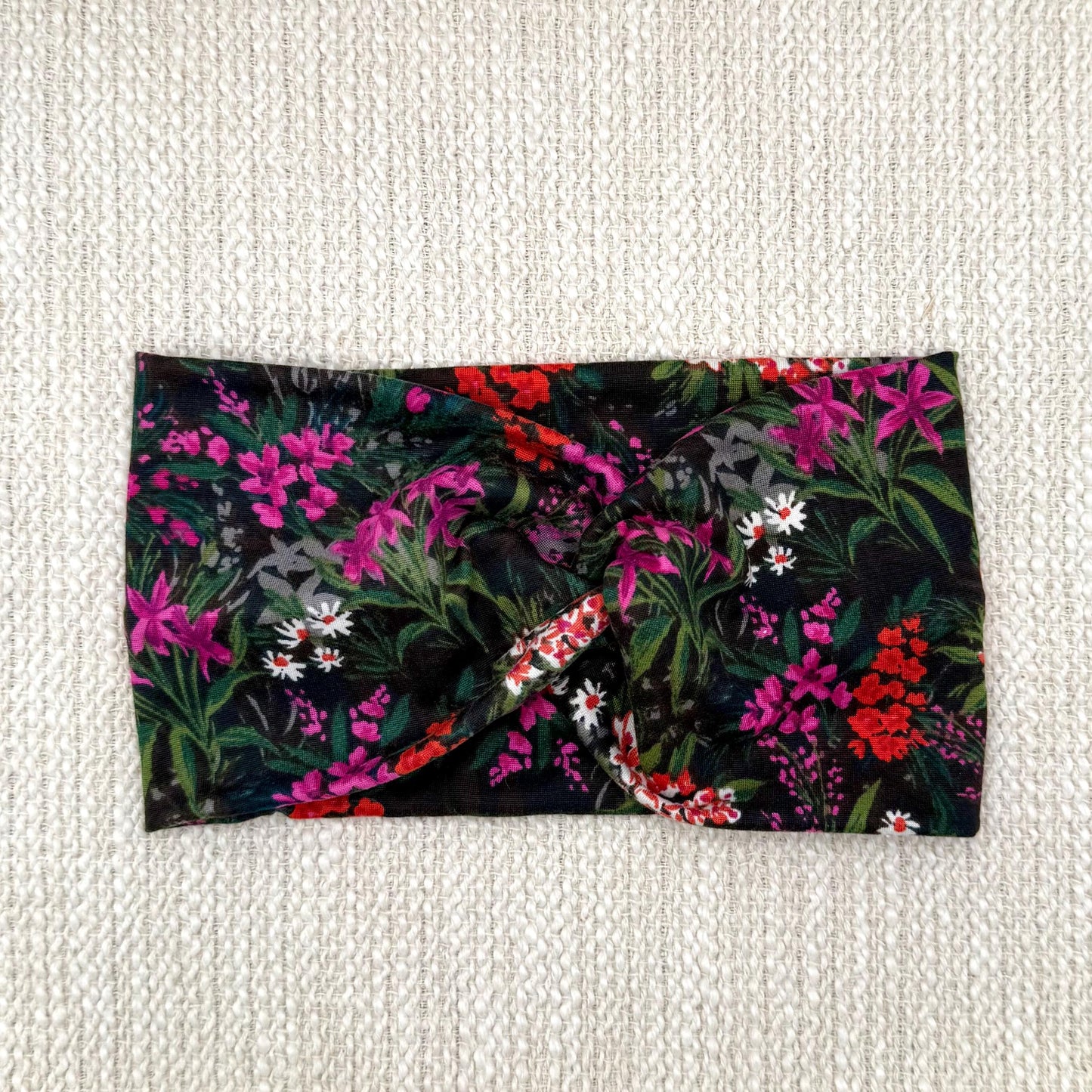 Wide, twisted headband in black with fuchsia and red/white floral print.