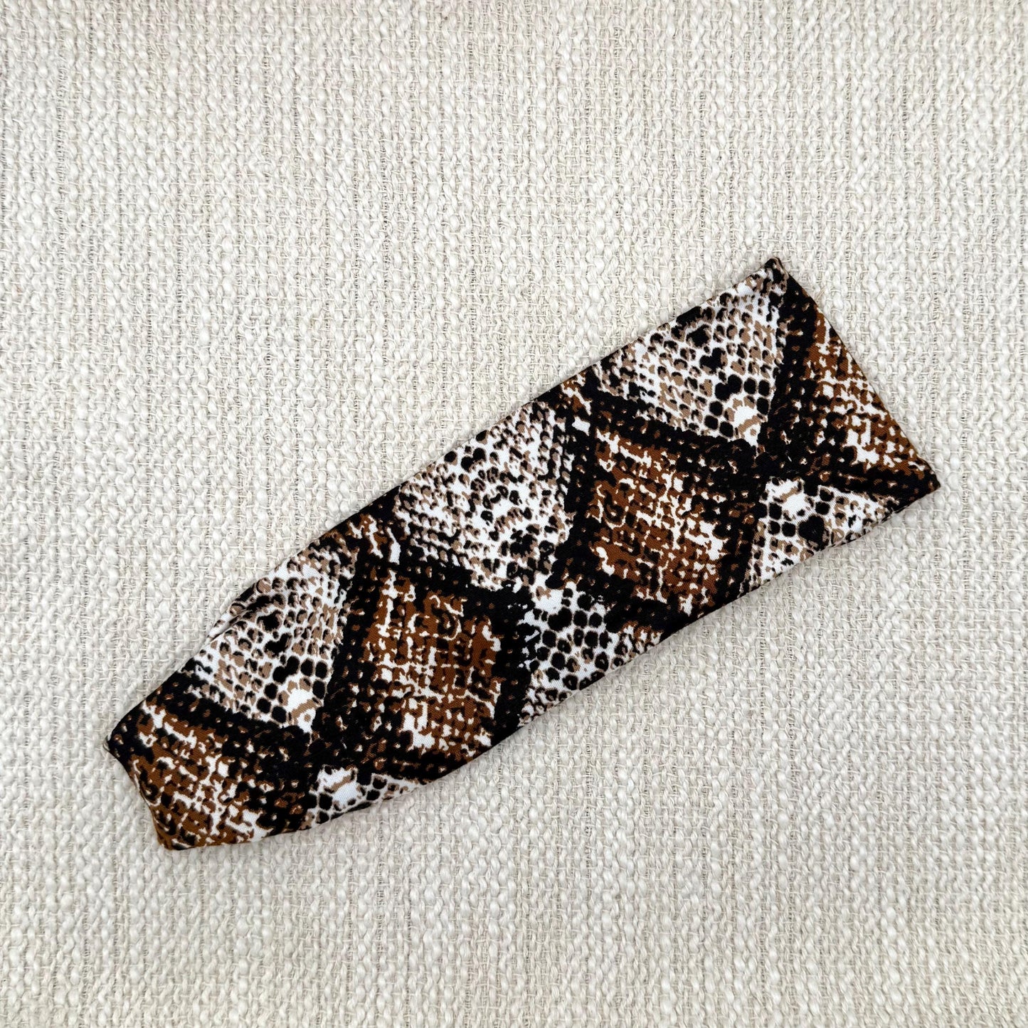 Flat, stretchy headband with brown snakeskin print.
