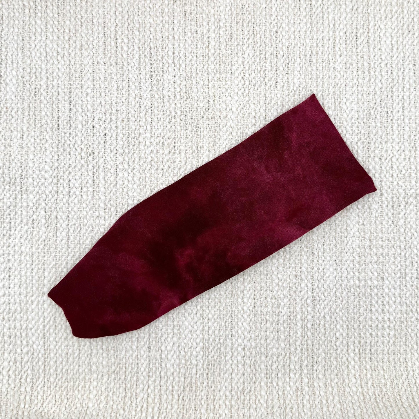 Flat, stretchy headband in maroon color tie dye print.