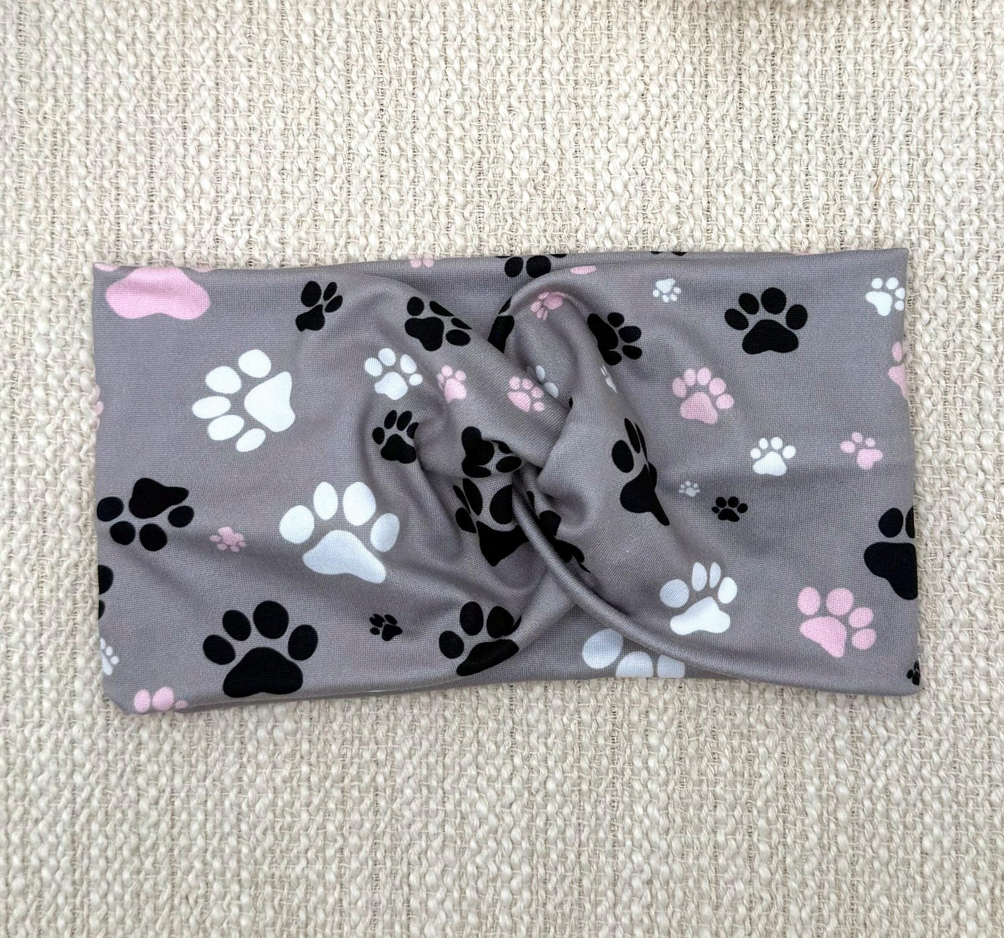 Wide, twisted, gray headband with pink, black, and white dog paw print.