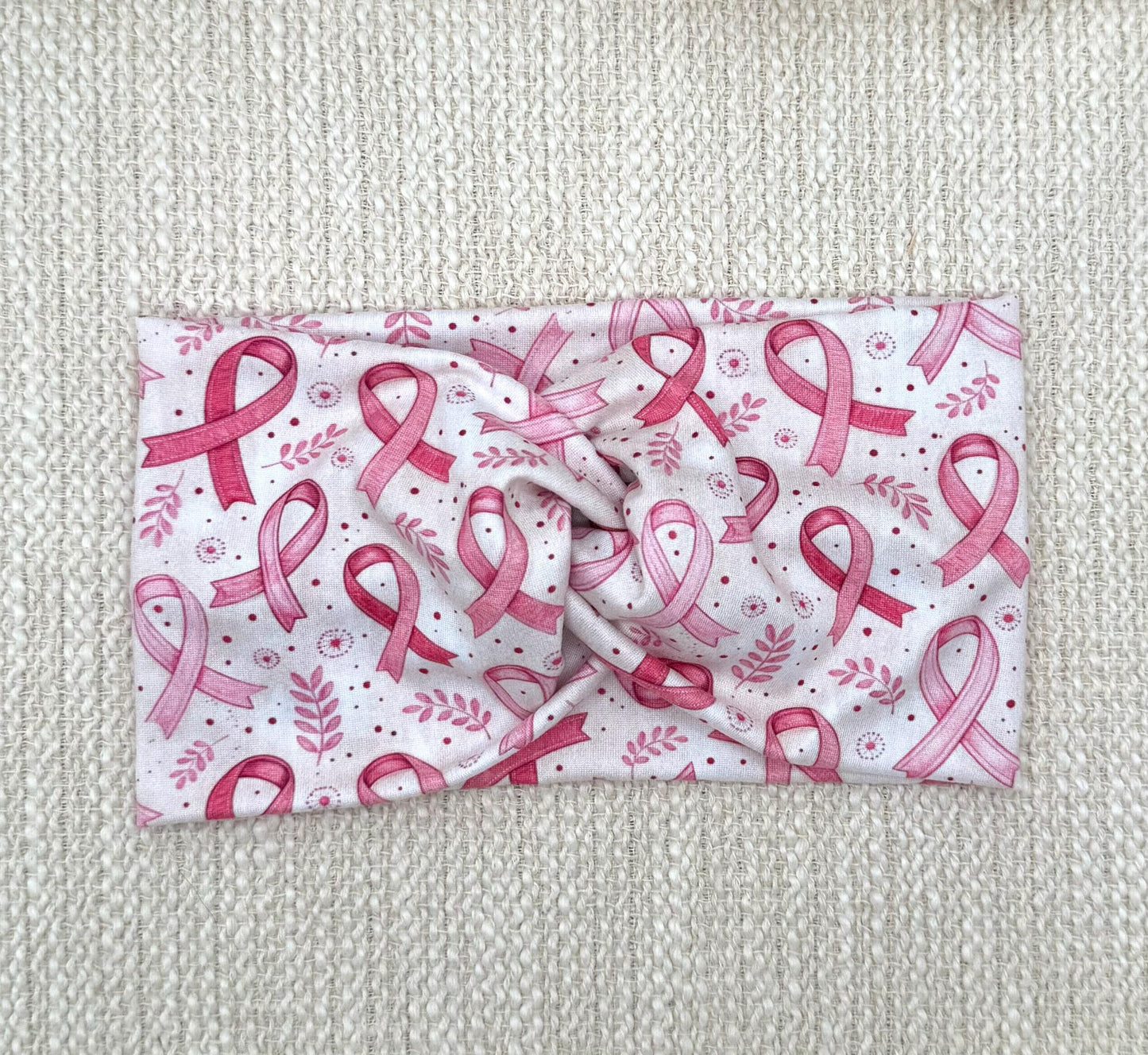 Wide, twisted, white/cream headband with pink ribbon and pink floral print.