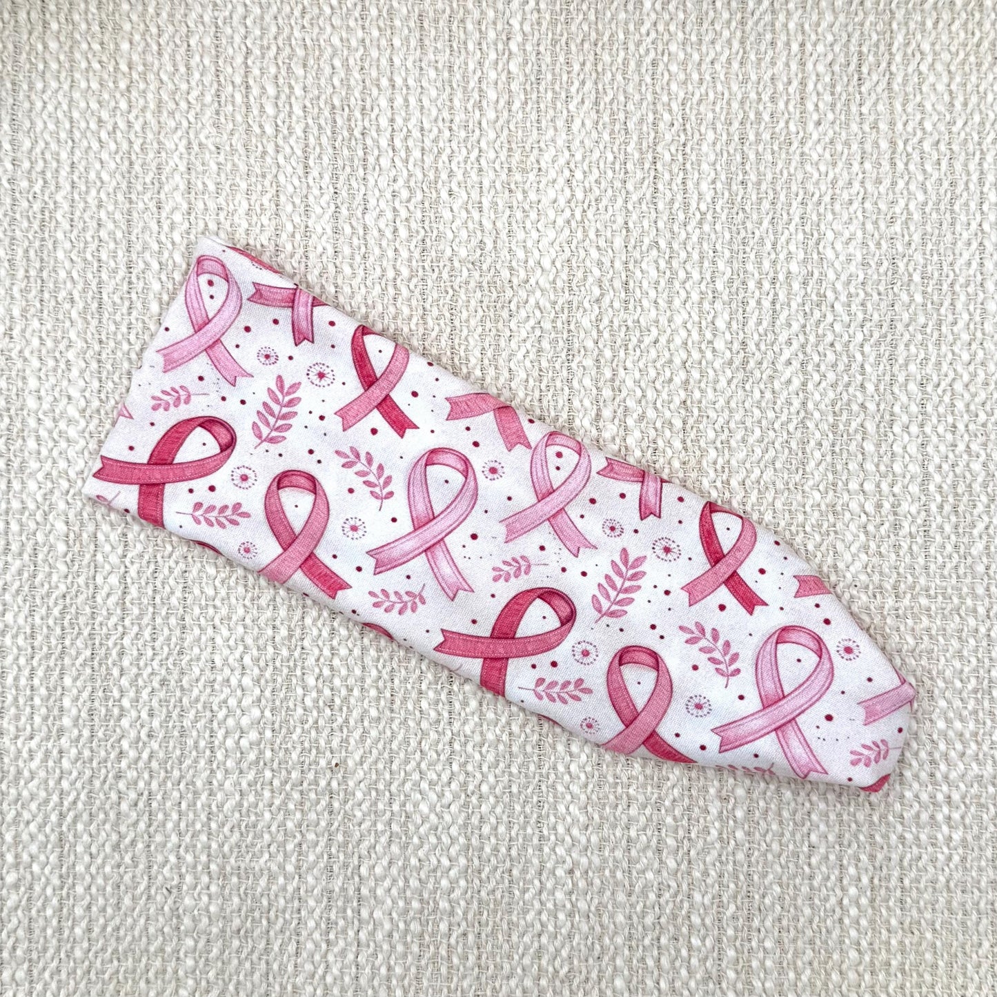 Flat, stretchy headband with pink ribbon, leaf, and polka dot print.