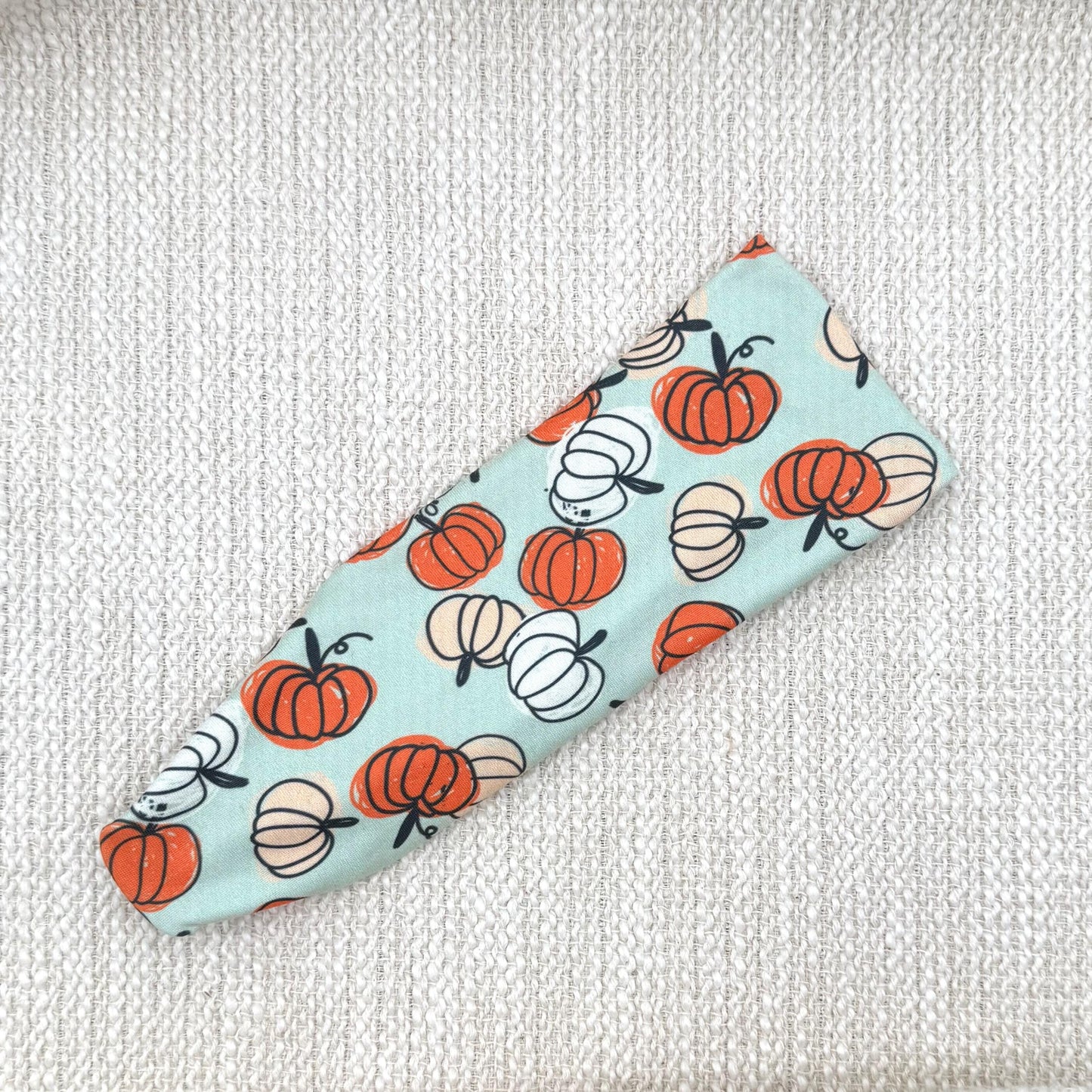 Flat, stretchy, mint green headband with pumpkin print.