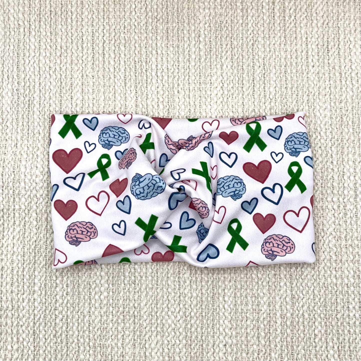 Wide, twisted headband with green ribbon, pink and blue brain, and pink and blue heart print.